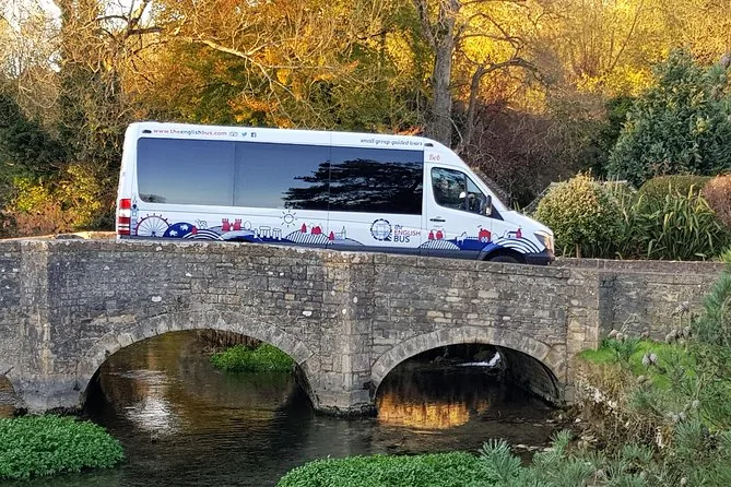 Ein Minibus überquert eine alte Steinbrücke in einem Cotswold-Dorf