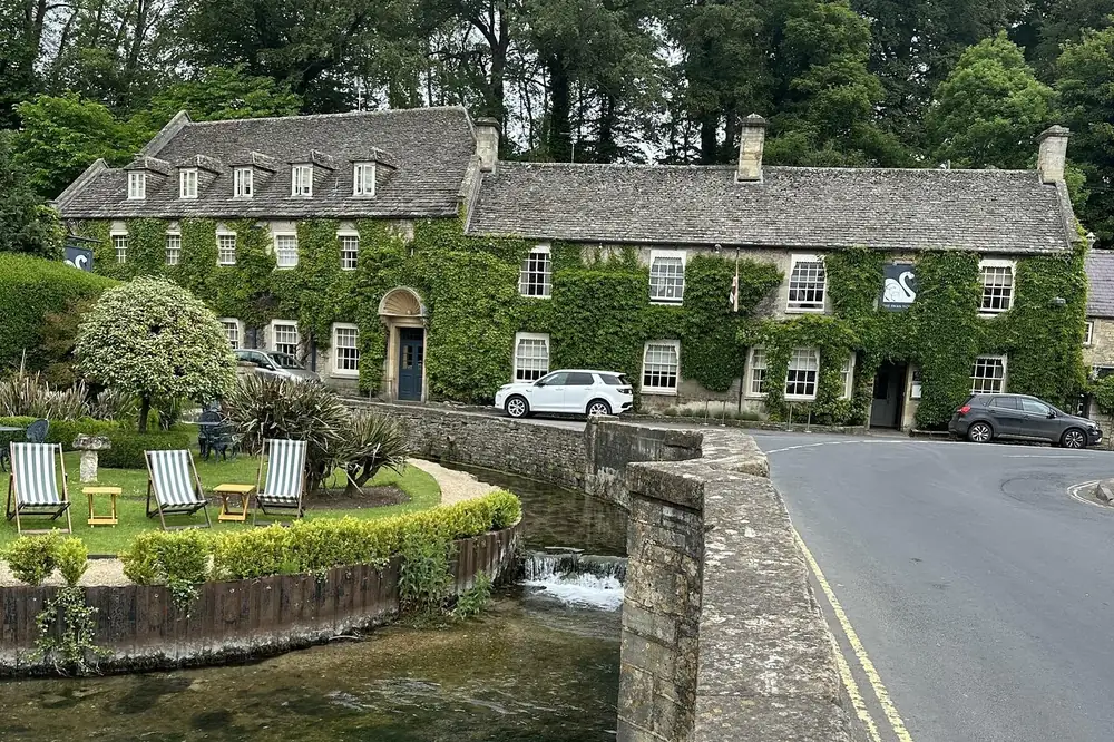 An ivy-covered stone building beside the river in Bibury